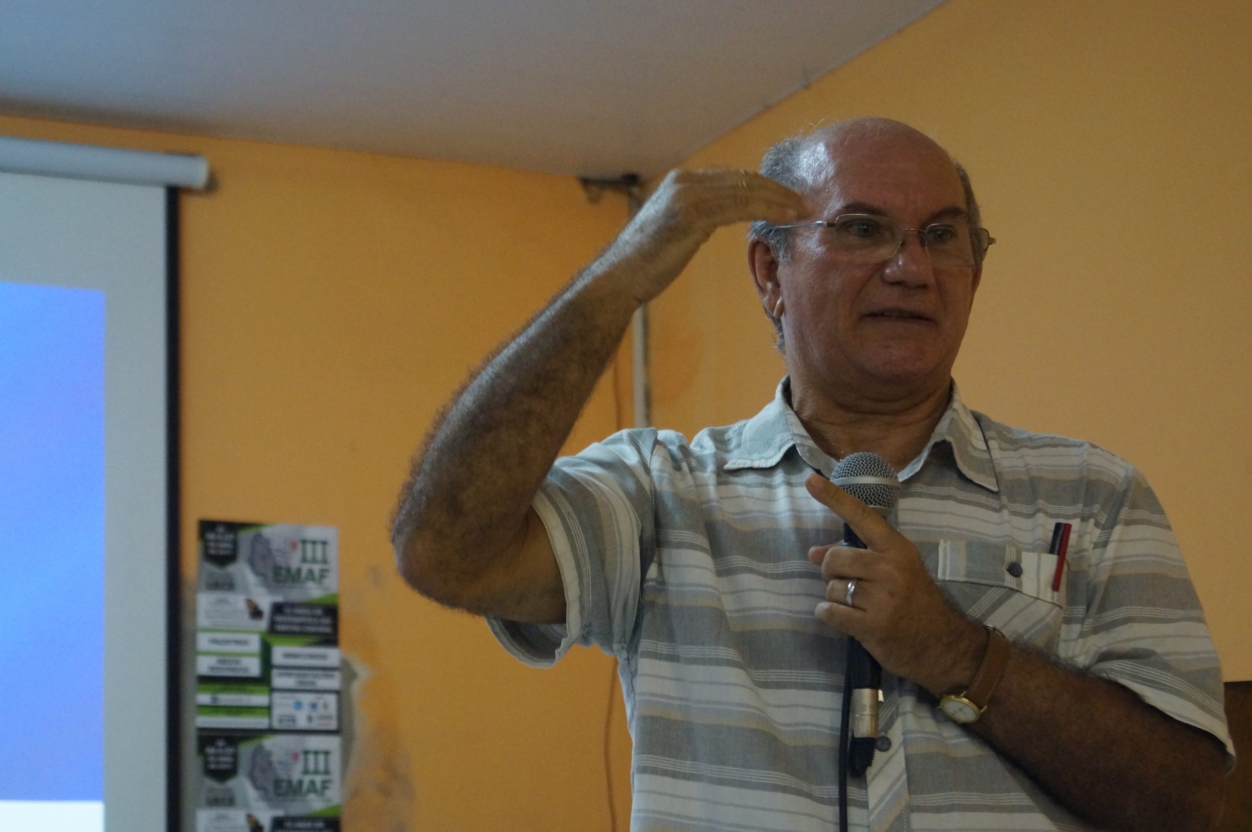 Fotografia do professor Herminio Borges Neto falando com um microfone e gesticulando durante uma palestra compondo a parte 1, Ligeiros aspectos biográficos, do e-book "Fedathi: trilhas construídas e contribuições para a Educação"